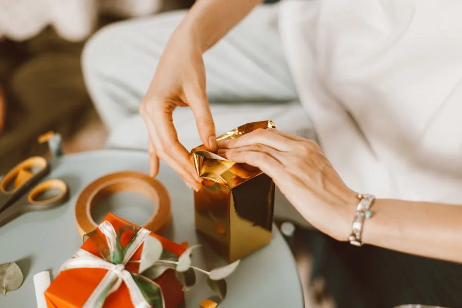 Hands wrapping gold and red presents in a cozy indoor setting, perfect for celebrations.