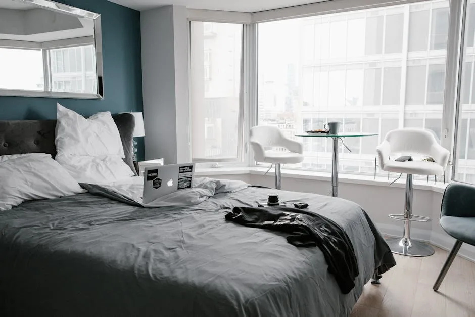 Contemporary hotel room in Toronto with bed, laptop, and city view.