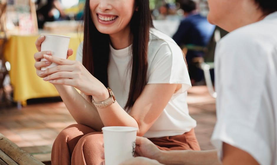 Two friends enjoying a coffee break outside, sharing smiles and conversation.