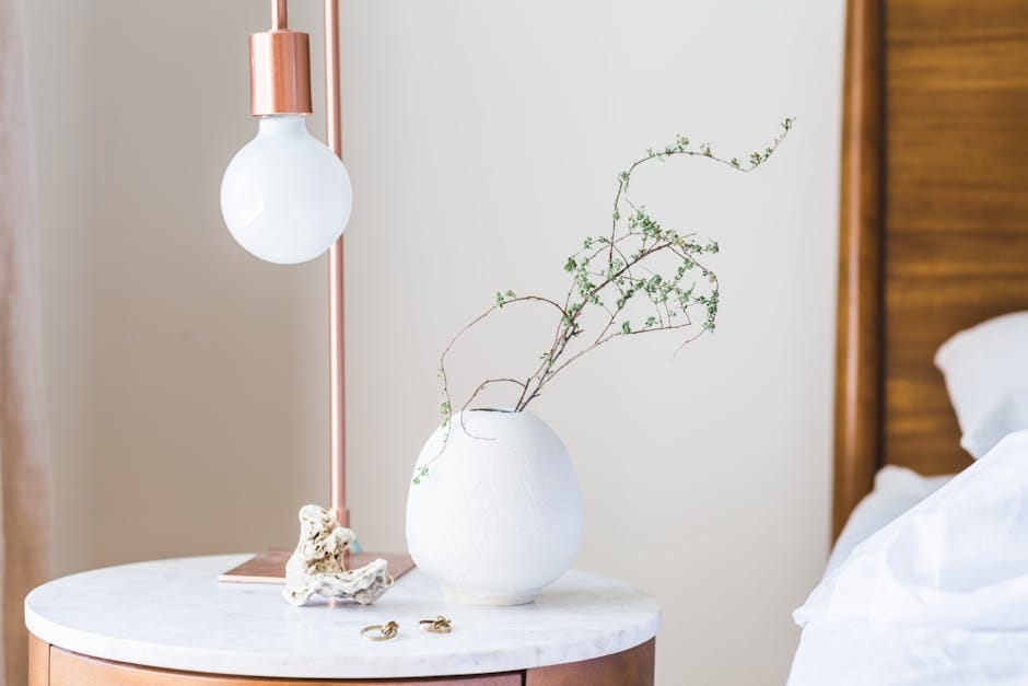 Stylish bedroom with a minimalist lamp and vase on a marble side table.