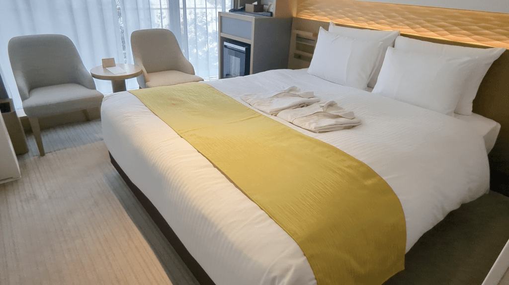 Guest room in Hotel Metropolitan Kamakura featuring a spacious bed, modern furnishings, and large windows with views of Kamakura greenery.